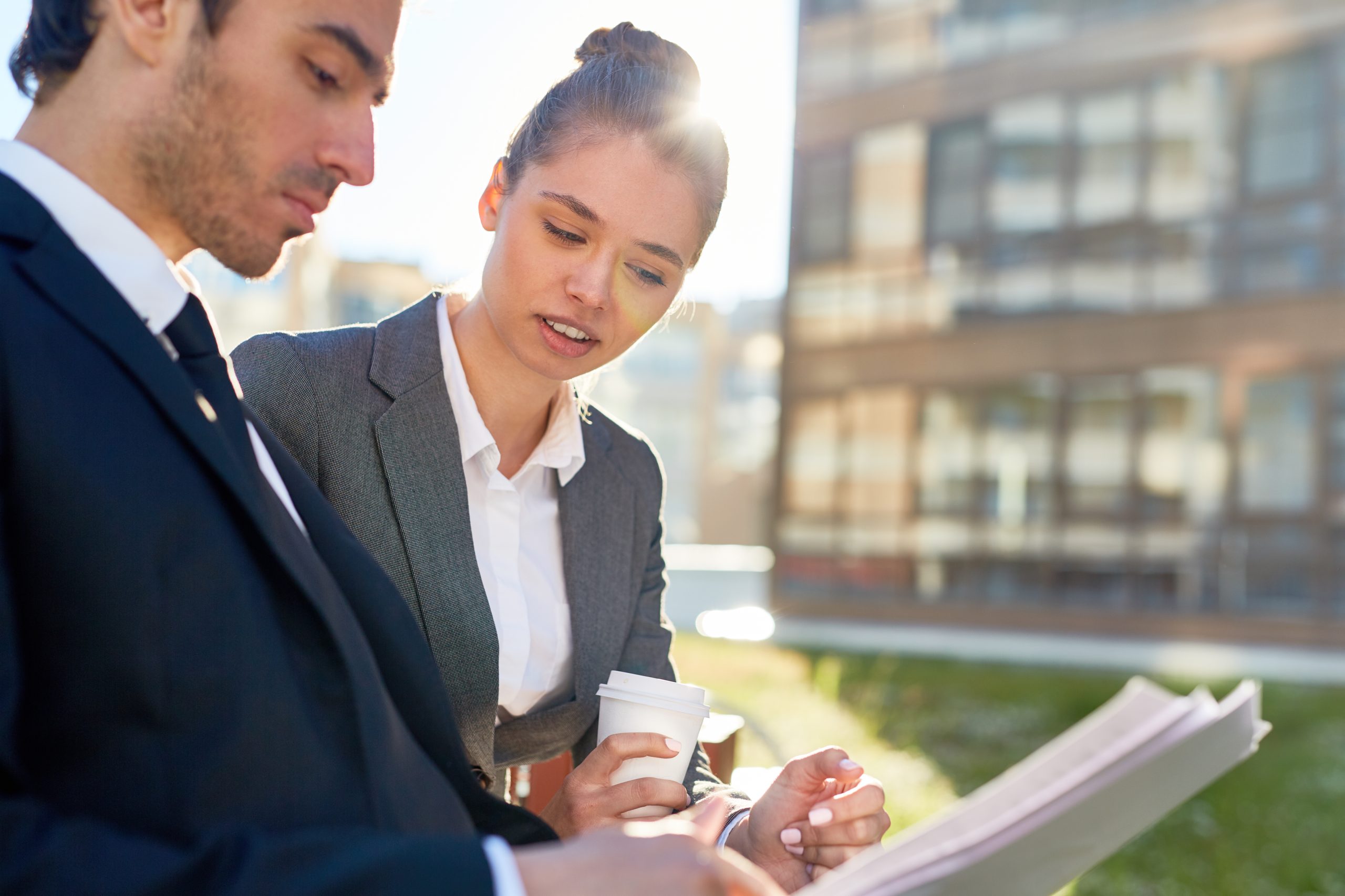 Businesswoman discussing papers with colleague outdoors